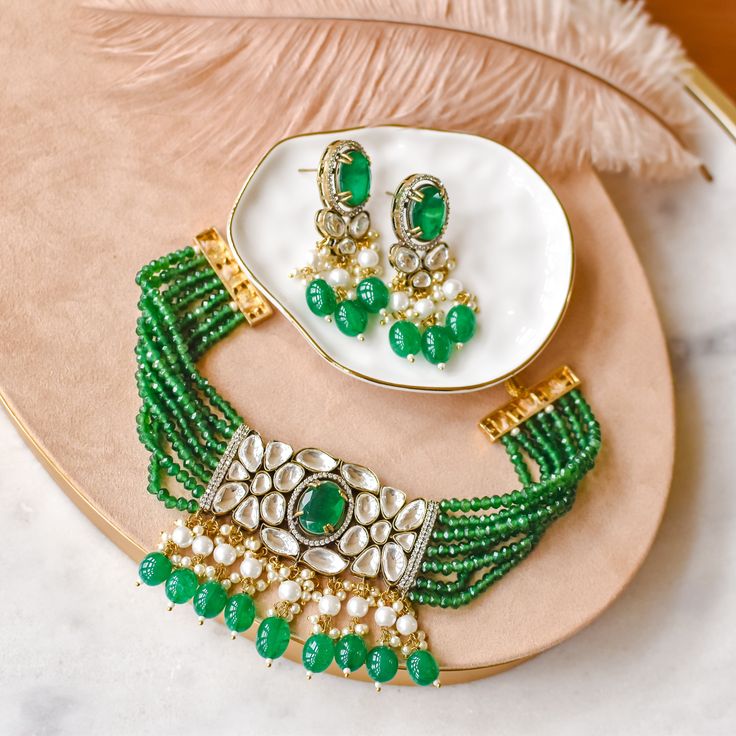 A celebratory set for those who wants a little extra glam! Beautiful piece exuding charm and elegance with hues of the emerald stones and beads along with moissanite polki stones and pearl moti embellishments. The set includes a necklace and a pair of matching earrings. Gold-plated on high-quality brass as base metal. Made by order. Kindly allow 4-6 weeks for the delivery of this item. For custom or urgent requests, please contact support@alacouture.com. *Please Note: We use faux stones and beads in all of our jewelry. Green Jewelry With Gota Work For Celebration, Green Pearl Necklace For Wedding And Diwali, Green Chandbali Bridal Necklace For Eid, Festive Emerald Kundan Chandbali Necklace, Festive Chandbali Kundan Necklace With Emerald, Festive Emerald Jewelry Sets With Stone Work, Emerald Bridal Necklace With Stone Work For Festive Occasions, Festive Bridal Necklace With Emerald Stone Work, Festive Emerald Jewelry Sets