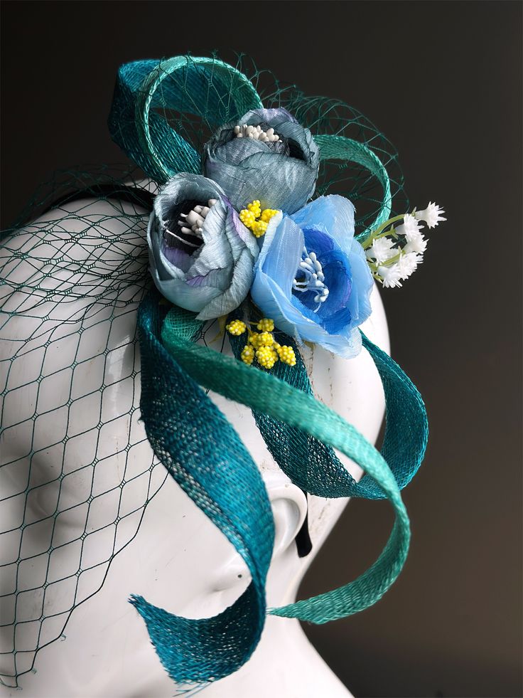 This sophisticated Fascinator hat features a delicate arrangement of soft blue flowers, accented by a luxurious turquoise teal sinamay ribbon and a matching fine net veil. Perfect for weddings, high tea, garden parties, or any elegant event, the Aqua Bloom Veil adds a touch of vintage charm and refined beauty to your ensemble. with delicate attention to detail, this Easter fascinator features a stunning array of lovely blue flowers delicately arranged on a blue base with netting. Age Group/Gende Easter Fascinator, Soft Blue Flowers, Mardi Gras Kid, Kids Party Packs, Veil Fascinator, Net Veil, Female Mask, Fascinator Hat, 1920s Flapper