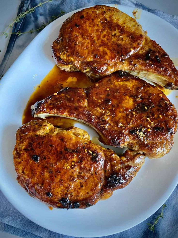 two pieces of meat sitting on top of a white plate covered in gravy