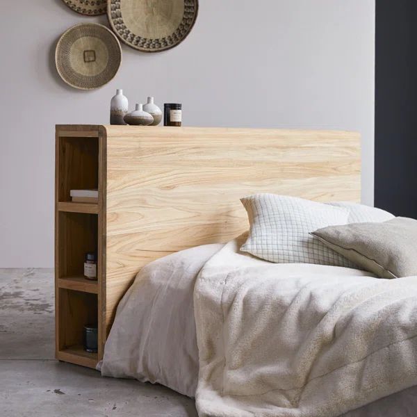 a bed with white linens and pillows in a bedroom next to two baskets on the wall