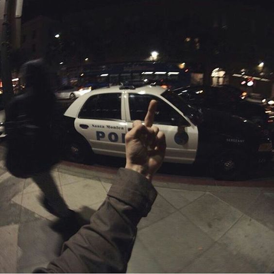 a police car parked in front of a parking lot with someone pointing at the camera