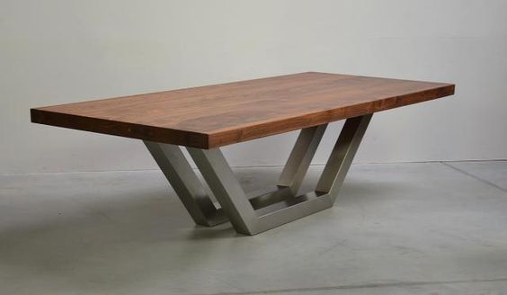 a wooden table sitting on top of a cement floor next to a white wall in an empty room