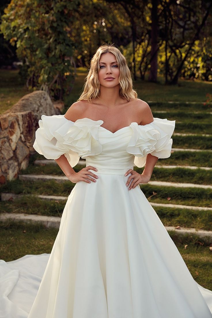 a woman in a white wedding dress posing for the camera with her hands on her hips