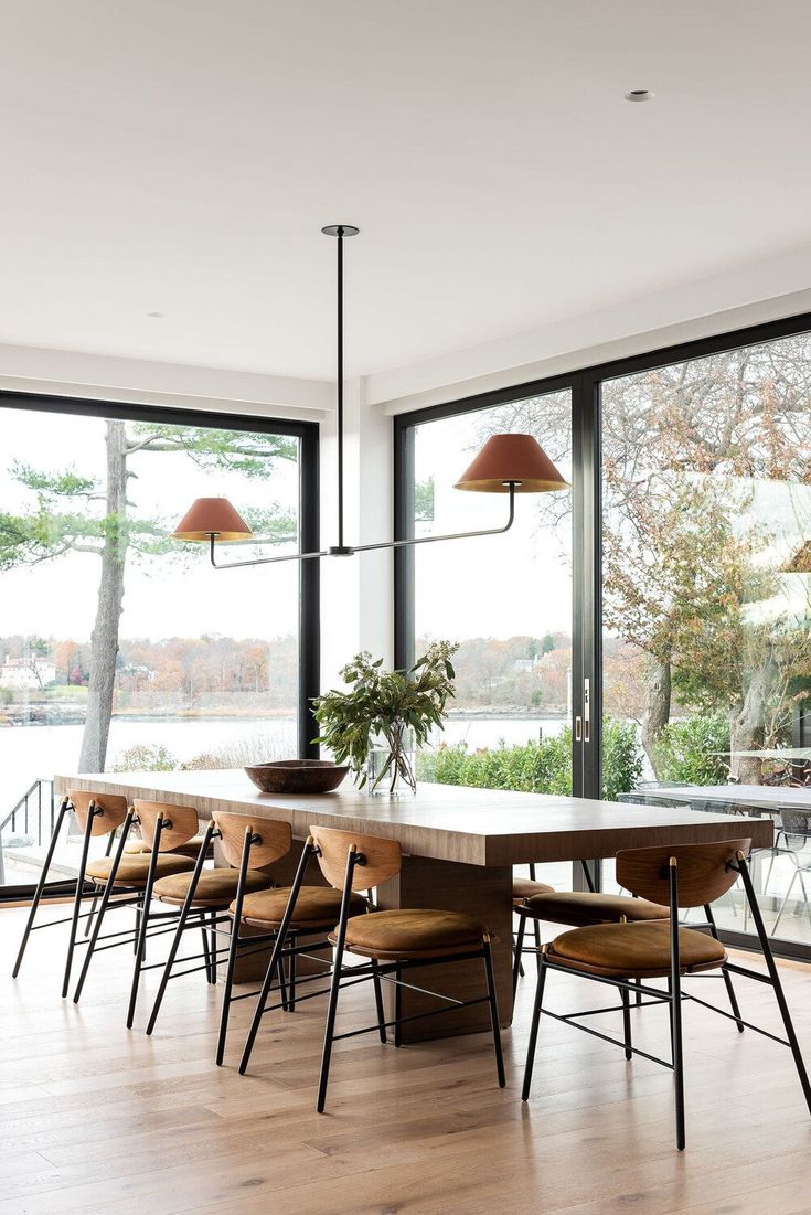 the dining room table is surrounded by six chairs and two pendant lights that hang from the ceiling