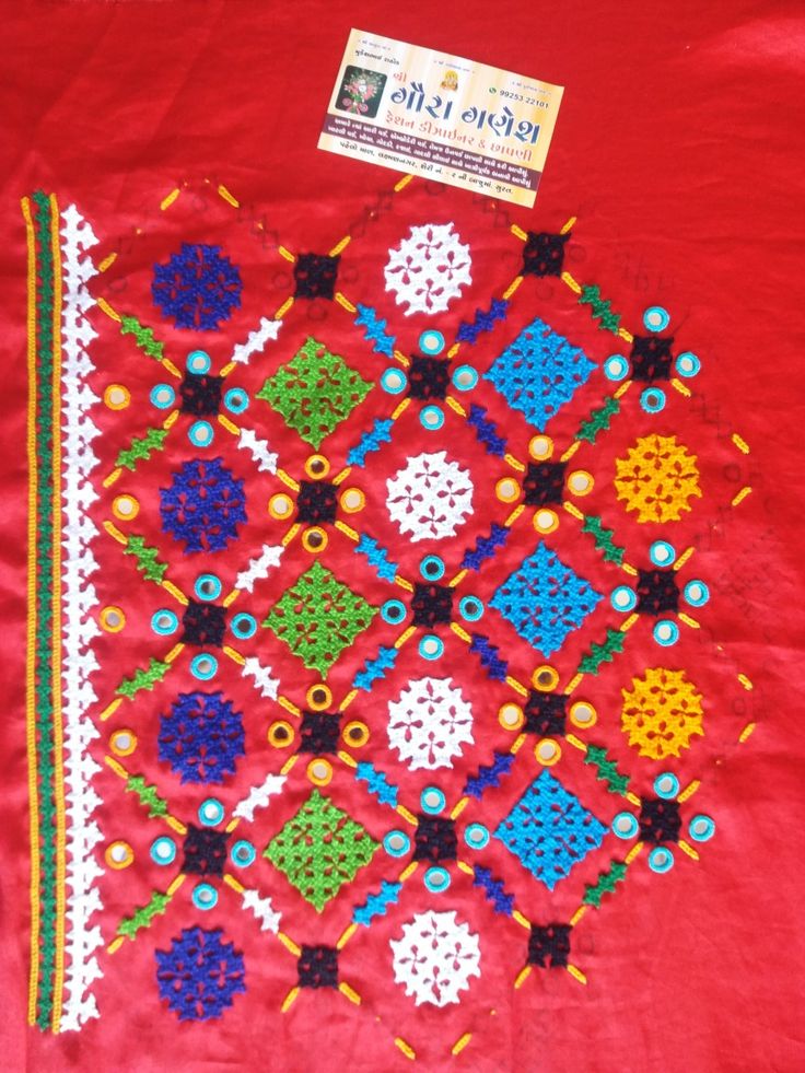 a red table cloth with an embroidered design on the front and side, along with a card