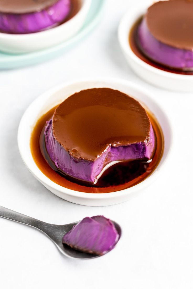 two small white bowls filled with purple and chocolate desserts on top of a table