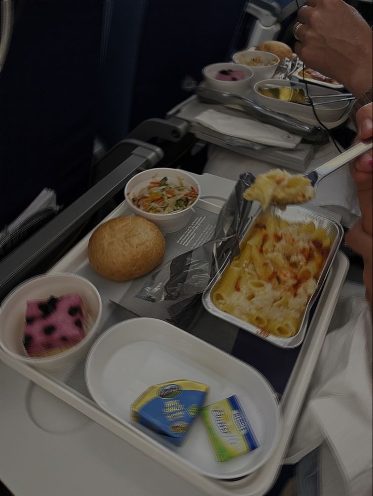 the trays are full of food on the plane, including pasta and other foods