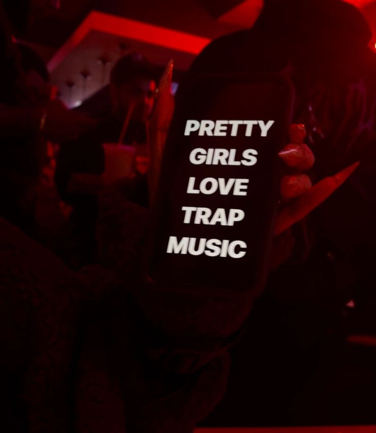 a person holding up a cell phone with the words pretty girls love trap music on it