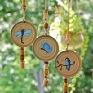 three wind chimes with blue birds on them hanging from the side of a tree