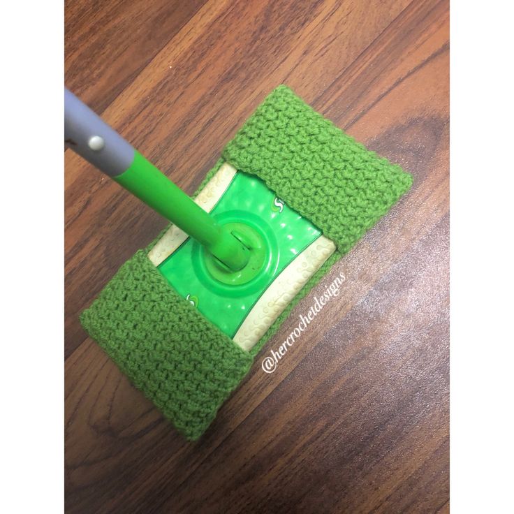 a green mop on top of a wooden floor