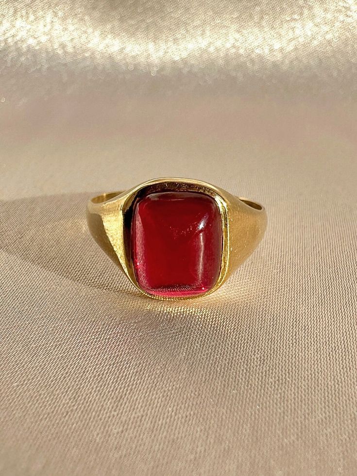 Antique 18k yellow gold ring from the United Kingdom. This signet ring features a vibrant synthetic ruby cabochon.  Great antique condition Size: 7.5 resizable** Weight: 3.5 grams Band: 11.1 mm (front), 1.7 mm (back) Synth Ruby: 8.3 mm x 10.0 mm  Hallmarks:18CT Please note, vintage and antique jewelry may come with imperfections commensurate of their age. To see more photos and videos of this piece, visit our Instagram: www.instagram.com/23carat PLEASE READ ALL POLICIES regarding shipping, returns, tax, etc Modern Gold Signet Ring With Cabochon, Formal Gold Cabochon Signet Ring, Heirloom Red Signet Ring With Polished Finish, Classic Red Ruby Ring, Oval Cabochon, Classic Red Ruby Ring With Oval Cabochon, Gold Ruby Ring Oval Cabochon With Polished Finish, Formal Red Domed Rings, Modern Yellow Gold Signet Ring With Cabochon, Classic Red Signet Ring For Formal Occasions