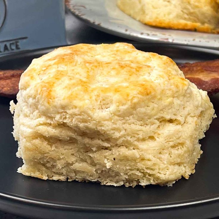 two plates with biscuits and bacon on them, one has a biscuit in the middle