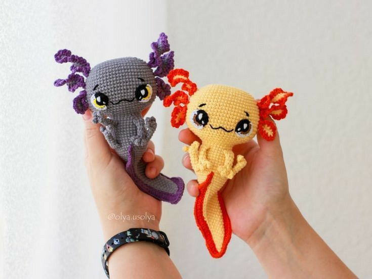 two crocheted sea creatures are held in their hands