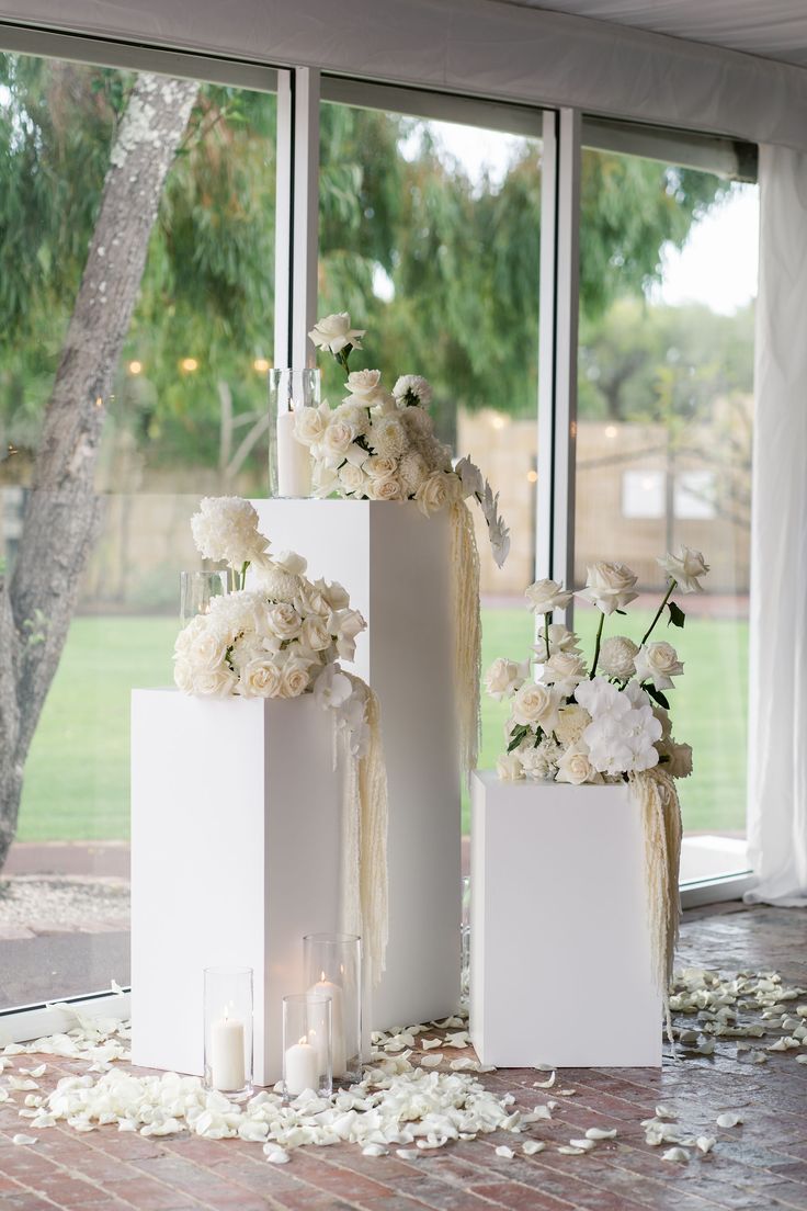 three white boxes with flowers and candles on the floor