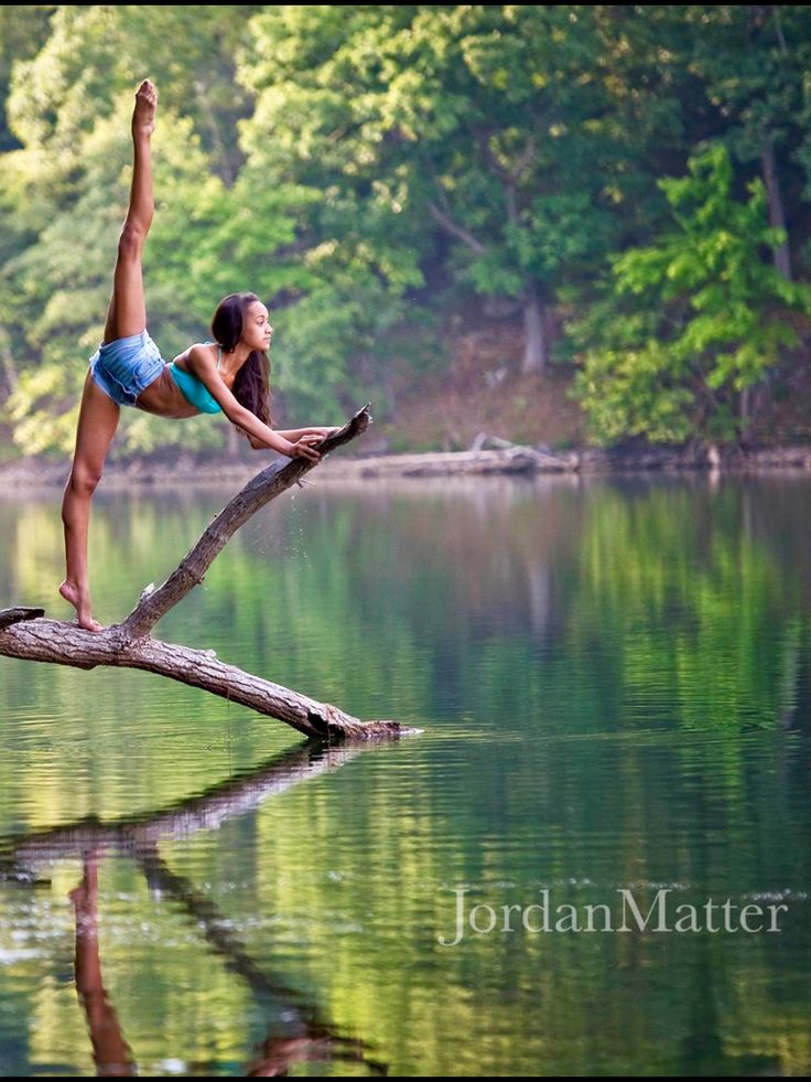 a woman is doing yoga on a log in the water