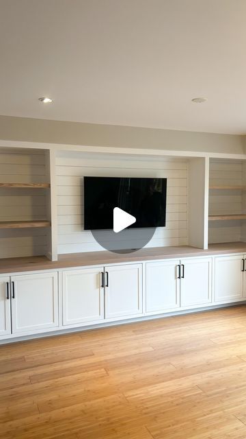 a living room with white cabinets and a flat screen tv mounted on the wall above it