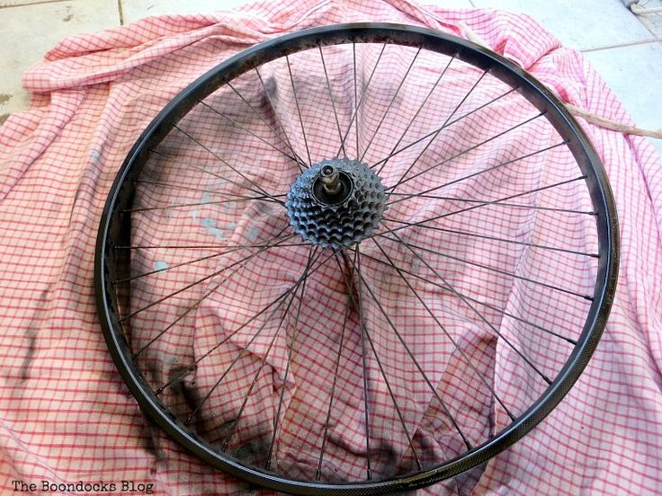 an old bicycle wheel is laying on the ground with tarp covering it's surface