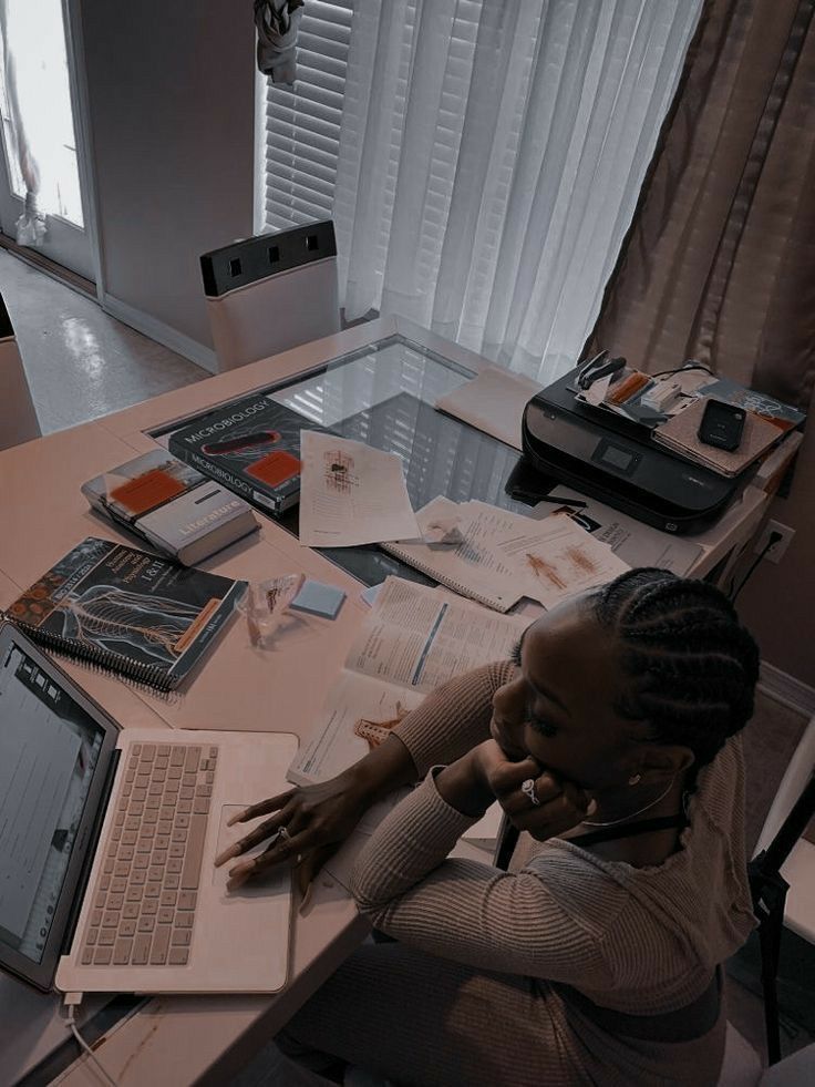 a woman sitting at a desk with a laptop computer and papers on the table in front of her