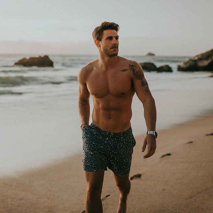 a shirtless man walking on the beach