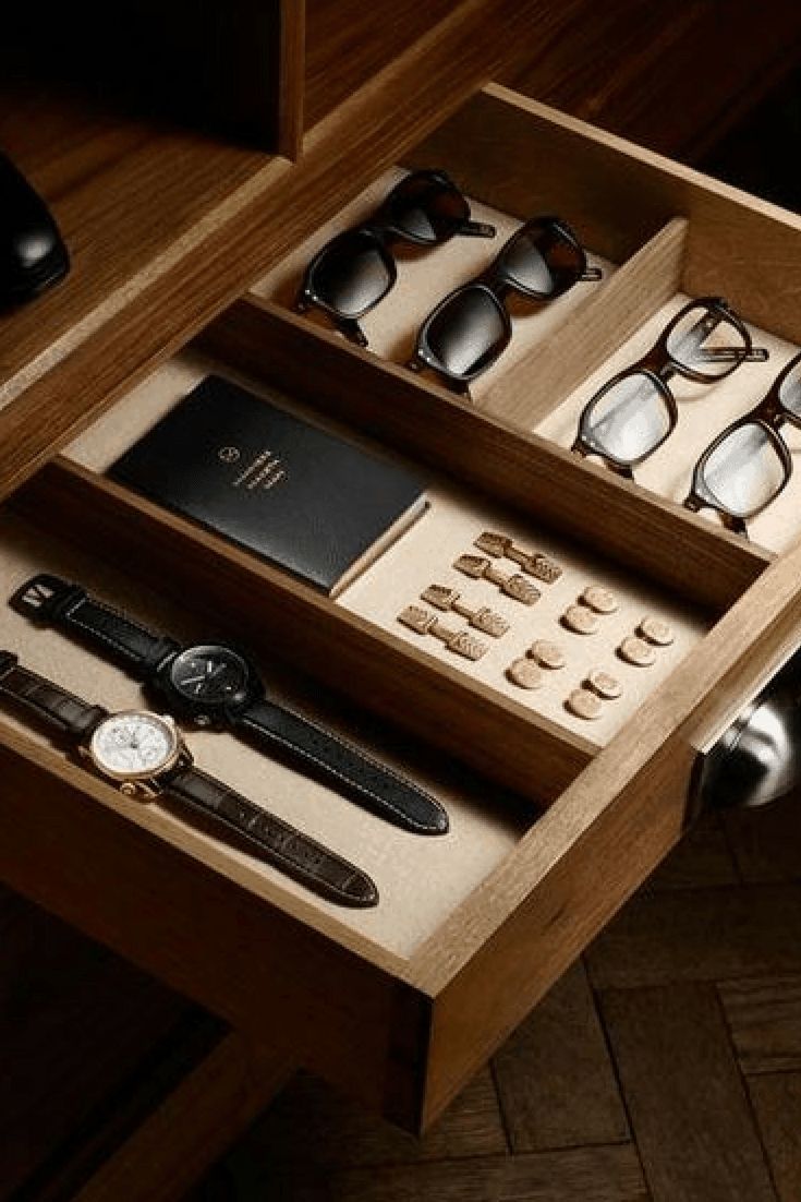 an open drawer with several pairs of glasses, watch and other items in it on a wooden table