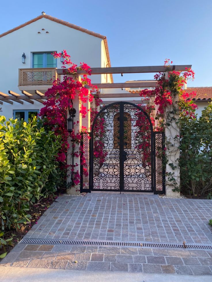 an entrance to a house with flowers on the wall and door, surrounded by greenery