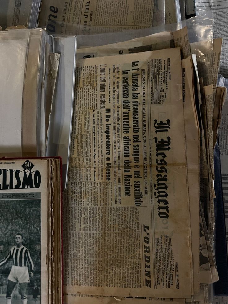 several newspapers are stacked on top of each other in front of a wall with newspaper clippings