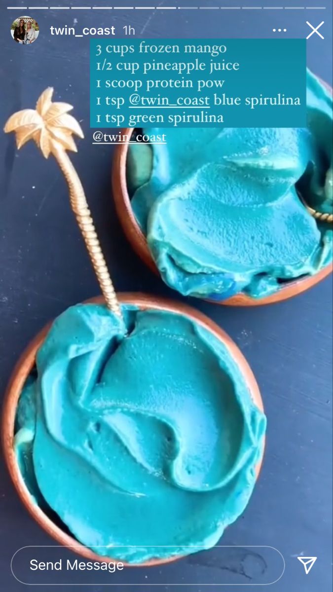 two small bowls filled with blue frosting next to a palm tree on top of a table