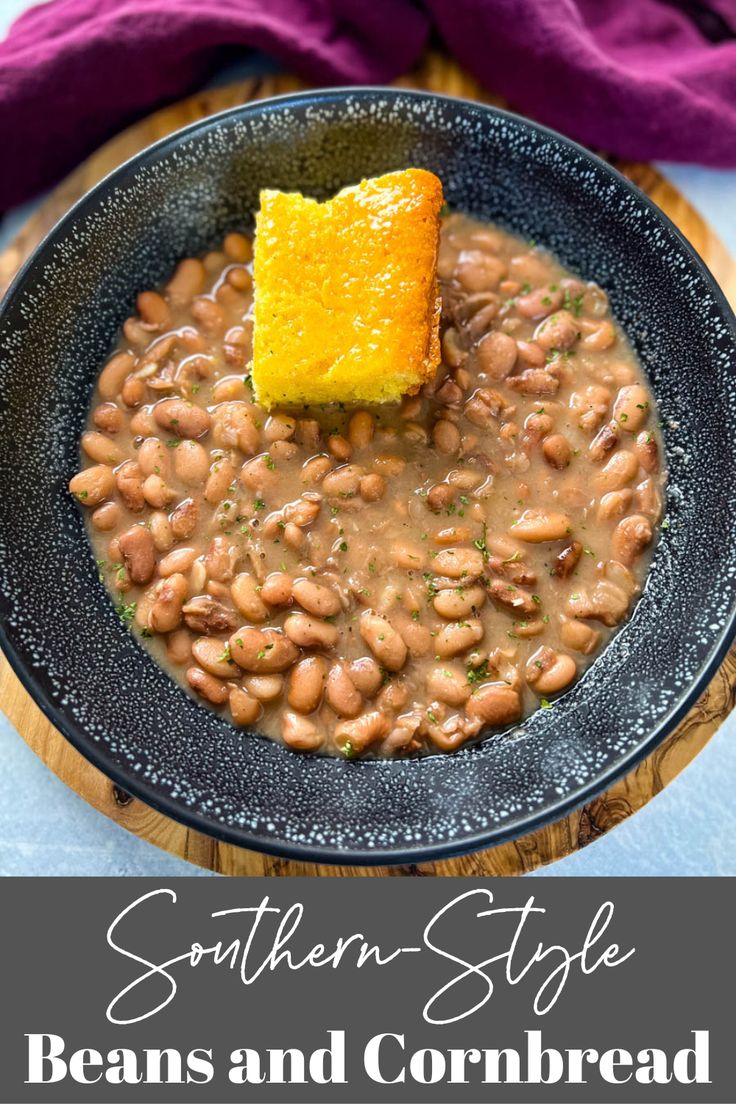 a black bowl filled with beans and a piece of bread