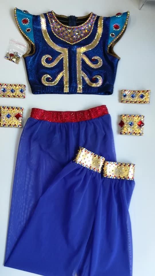 a blue outfit with gold sequins on it and other accessories laid out next to it