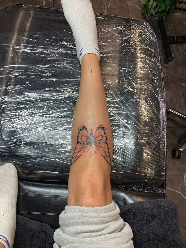 a woman's leg with a butterfly tattoo on her left arm and right leg