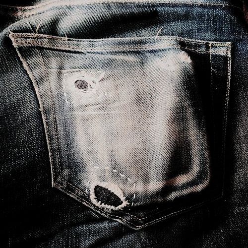 the back pocket of someone's jeans with holes in it and an eye patch