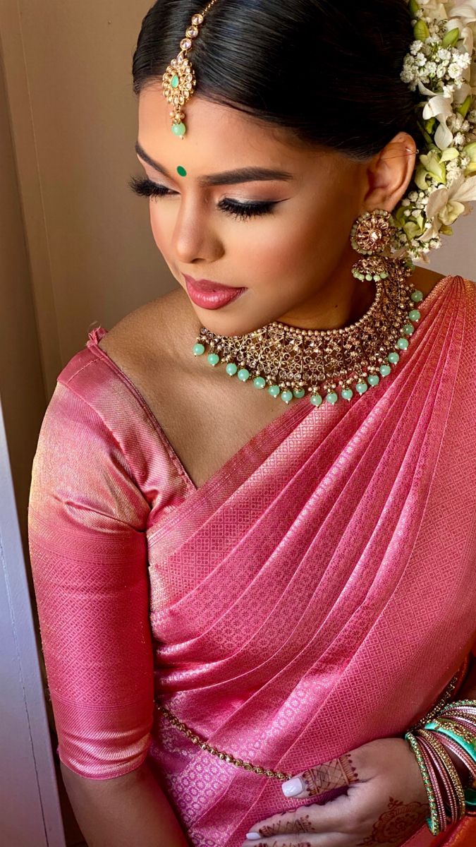 a woman wearing a pink sari and jewelry