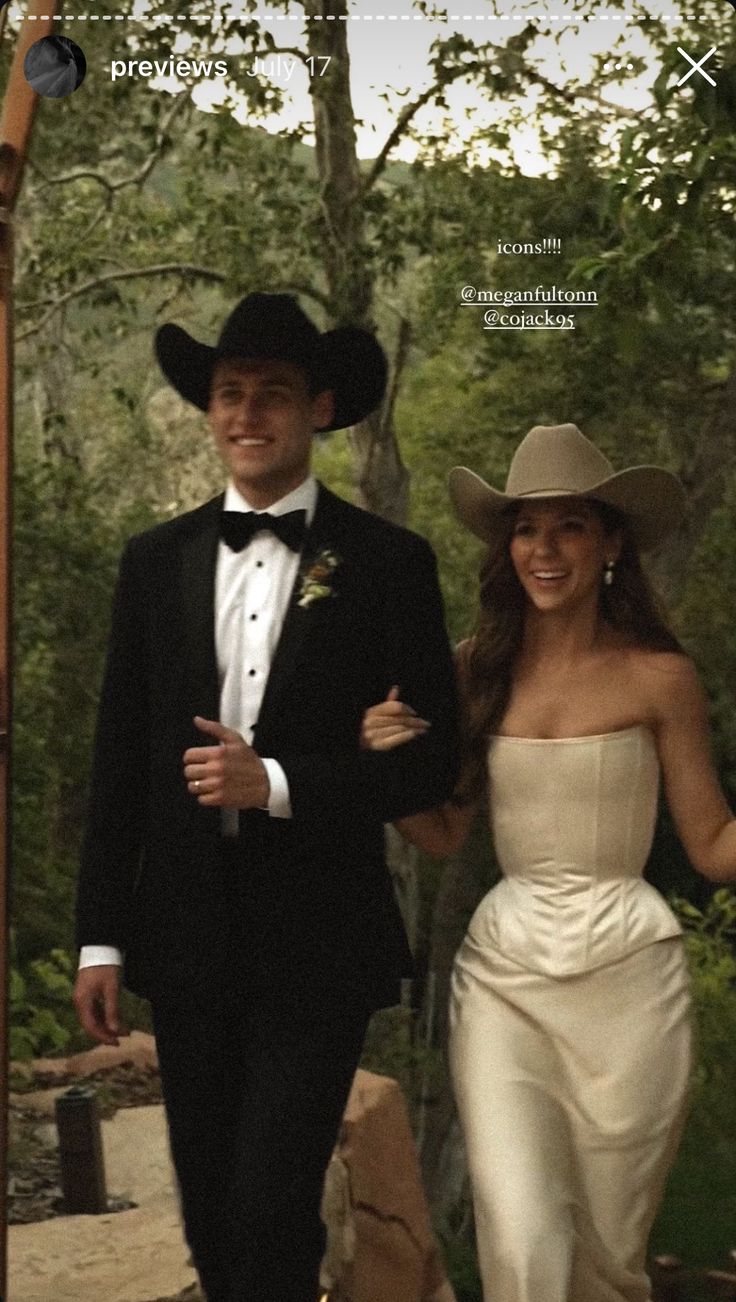 a man and woman dressed in wedding attire walking down a path with trees behind them