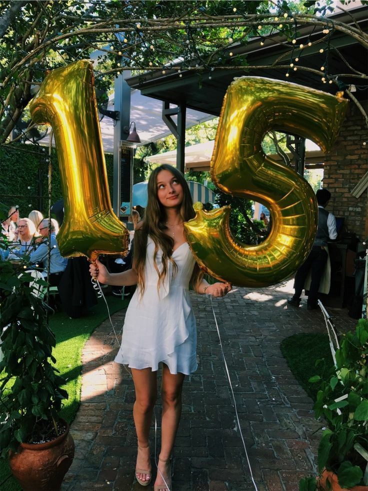 a woman holding up the number twenty five balloons