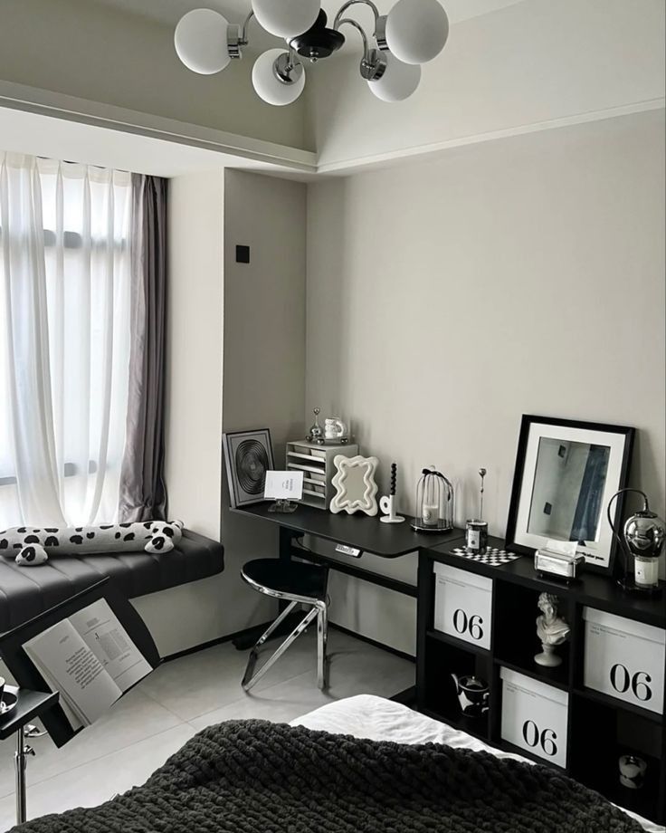 a black and white photo of a bedroom with a desk, bookshelf, and window