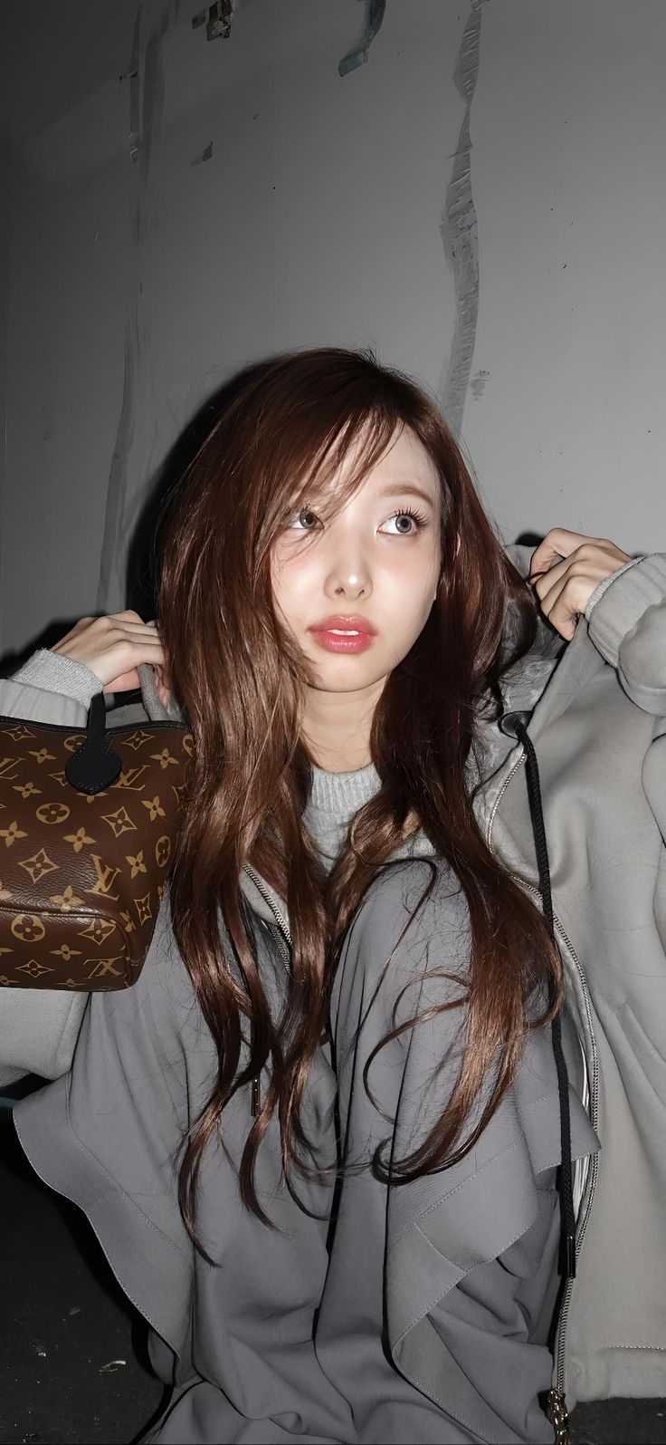 a woman with long brown hair is holding a handbag and posing for the camera