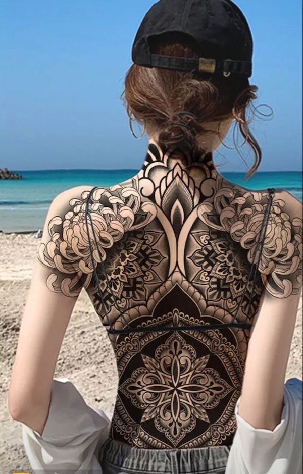 a woman sitting on the beach with her back to the camera