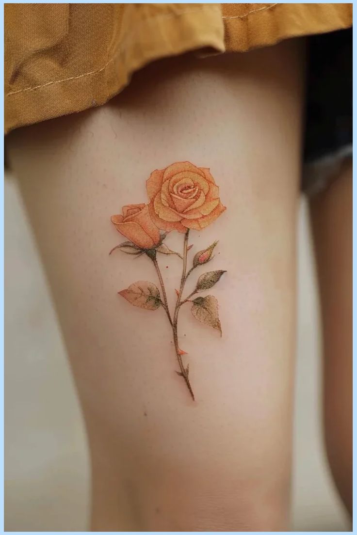 A delicate orange rose tattoo on a person's thigh. Yellow Orange Rose Tattoo, Pink And Yellow Rose Tattoo, Stop And Smell The Roses Tattoo, Orange Roses Tattoo, Tiny Yellow Rose Tattoo, Simple Yellow Rose Tattoo, Rose Tattoo On Buttocks, Peach Rose Tattoo, Two Rose Tattoo