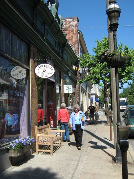 people are walking down the sidewalk in front of shops