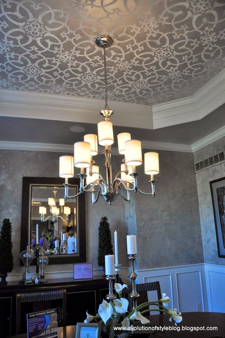 a chandelier hanging from the ceiling in a room with gray walls and white trim