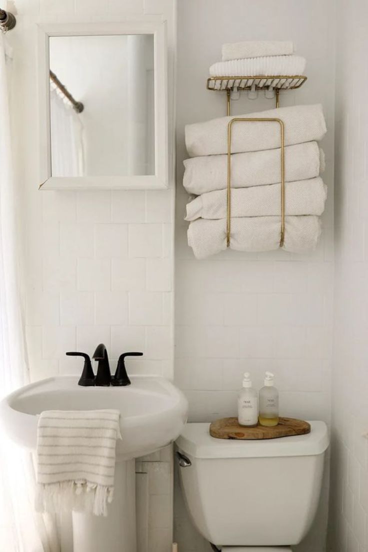 a white toilet sitting next to a sink in a bathroom under a mirror and towel rack