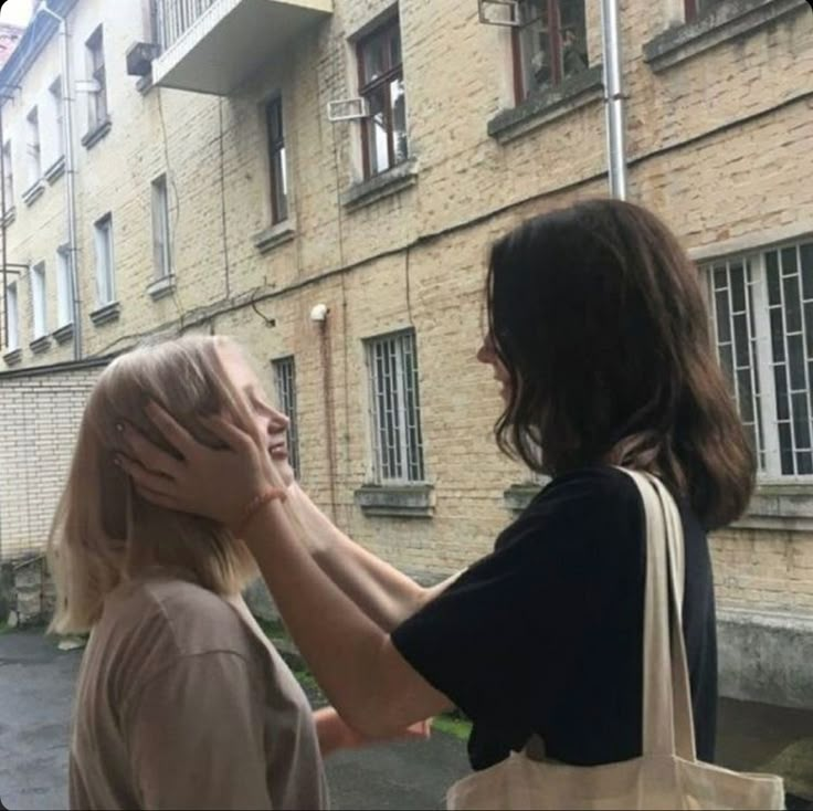 two women standing in front of a brick building