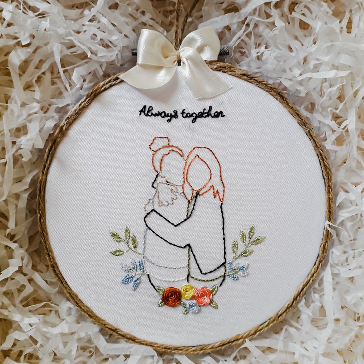 a white embroidered ornament with an image of two people hugging and the words always together on it