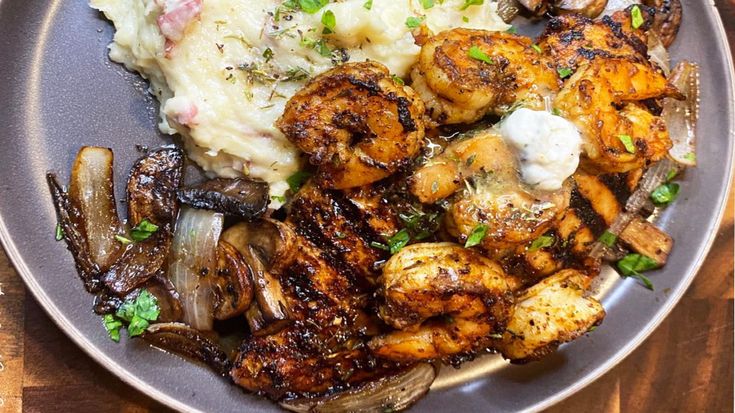 a plate filled with meat, potatoes and vegetables on top of a wooden table next to a fork