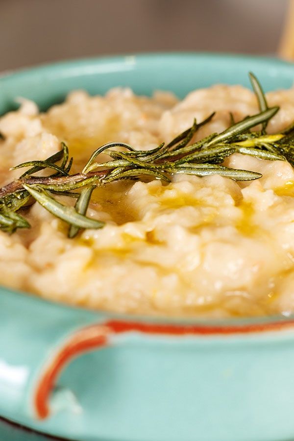 a blue bowl filled with mashed potatoes topped with rosemary