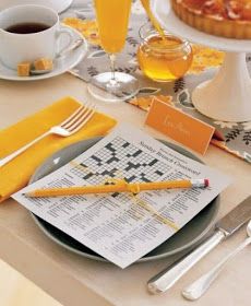 the table is set with orange and white plates, silverware, cups, and utensils