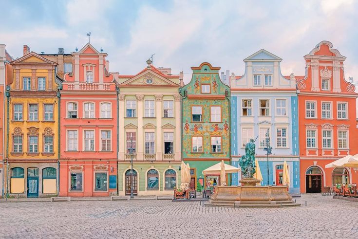 many colorful buildings line the street in front of a fountain