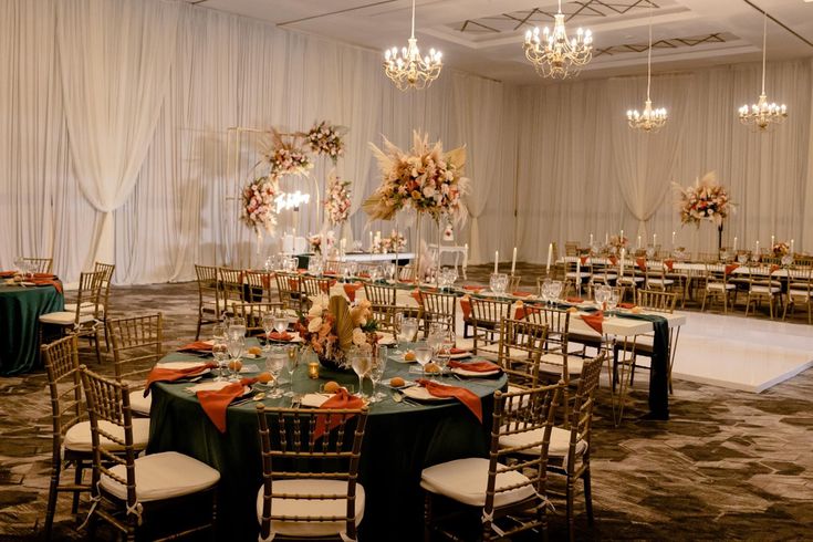 a banquet hall with tables and chairs set up for an event or function, decorated with floral centerpieces