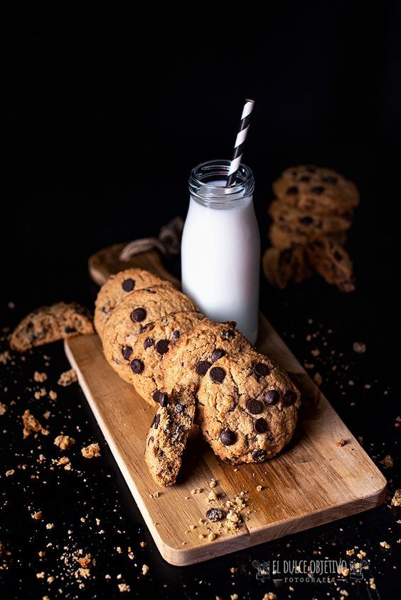 chocolate chip cookies and milk on a cutting board