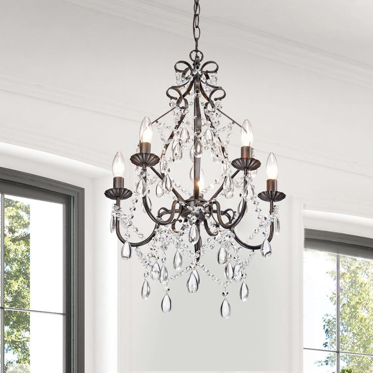 a chandelier hanging from the ceiling in a living room with white walls and windows